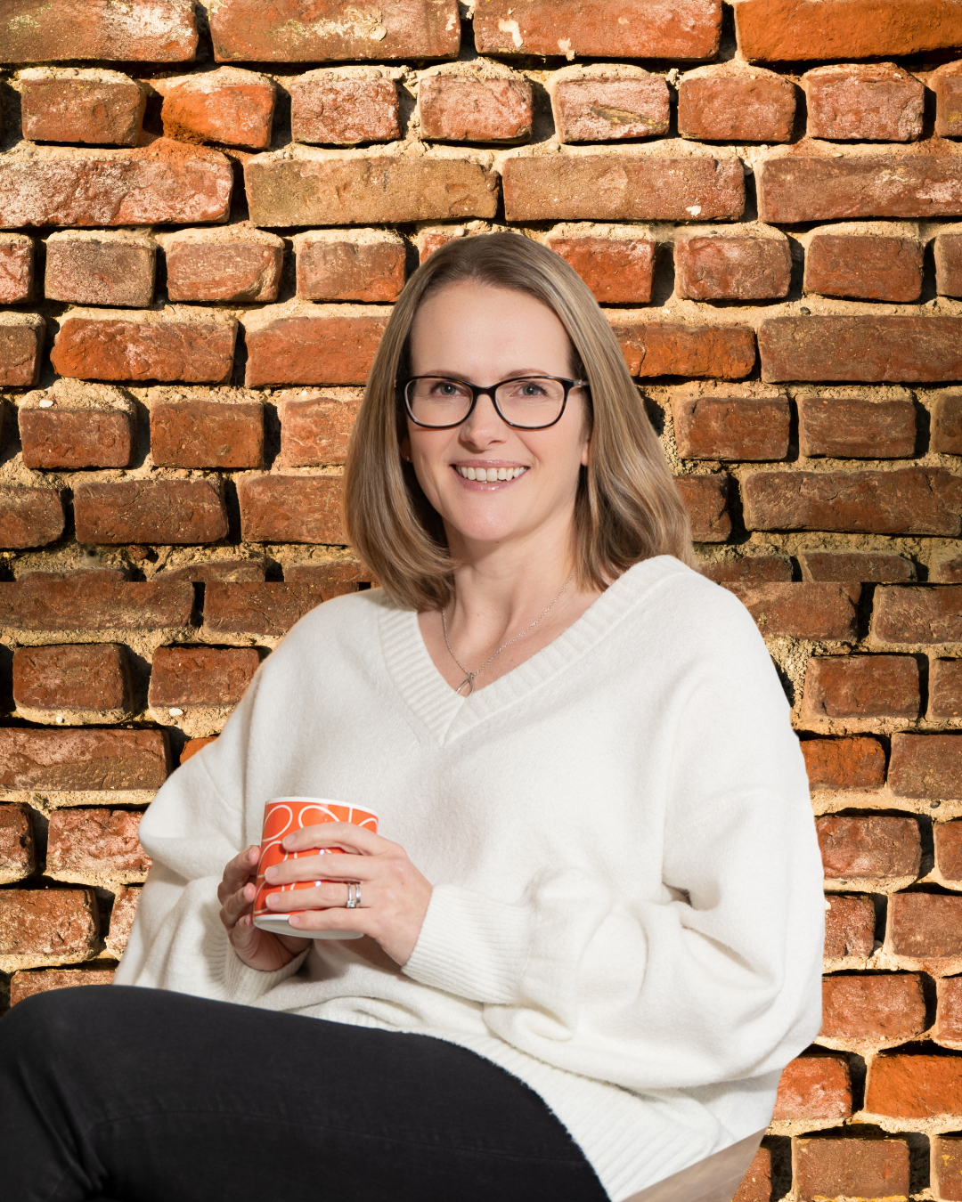 Aly sat in front of a brick wall.