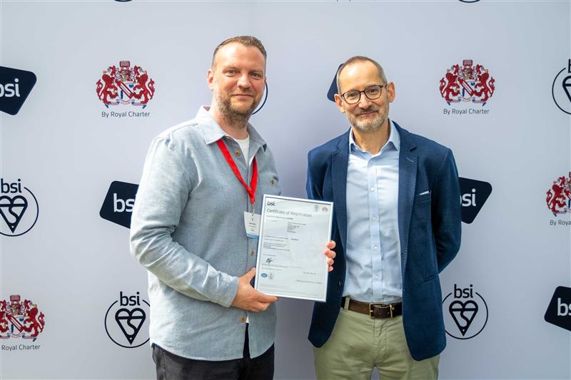 Two men stood in front of a screen holding a certificate award . 